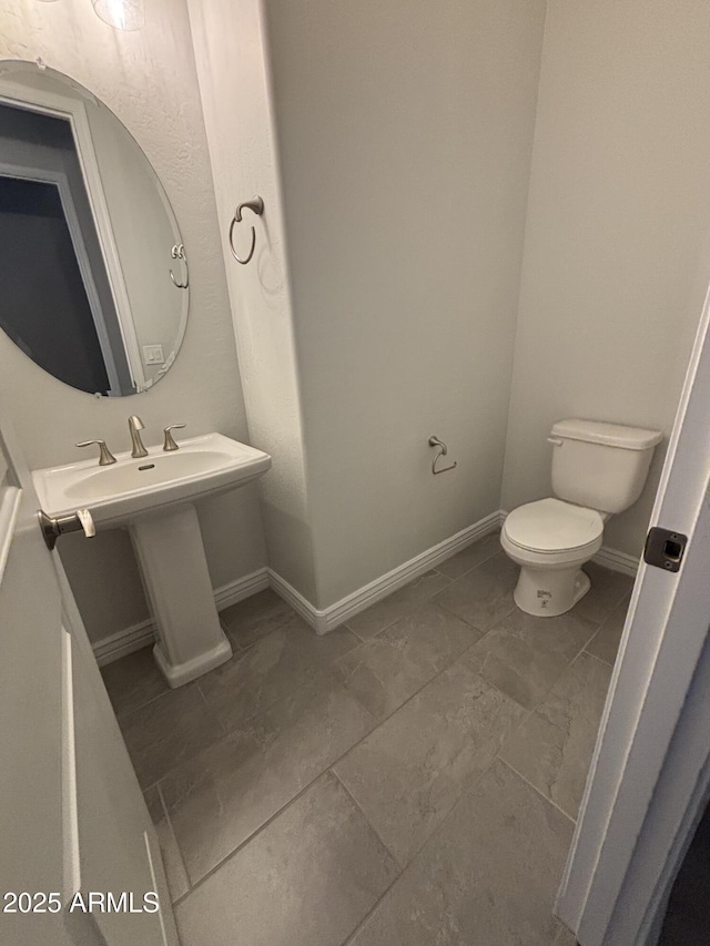 bathroom featuring toilet and baseboards