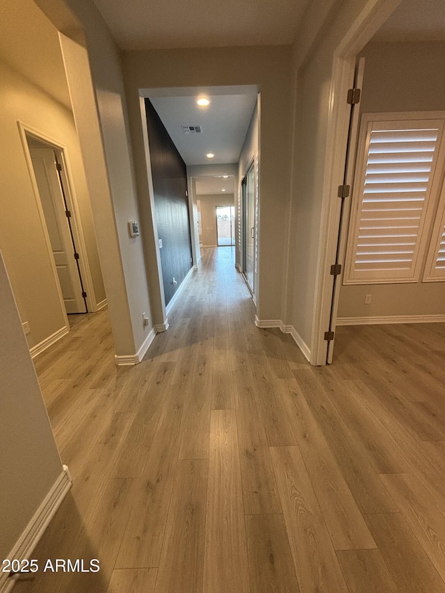 hallway with visible vents, baseboards, and wood finished floors