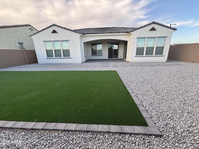 back of property with a tile roof, stucco siding, a lawn, a patio area, and a fenced backyard