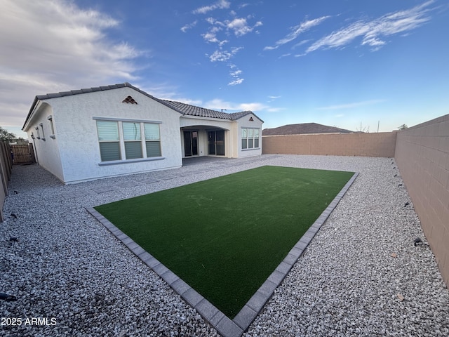 back of property with a fenced backyard, a tiled roof, a patio, and stucco siding