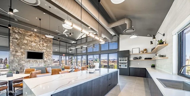 kitchen with light tile patterned floors, a towering ceiling, modern cabinets, open shelves, and a sink