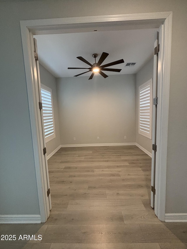 empty room featuring light wood finished floors, plenty of natural light, visible vents, and ceiling fan