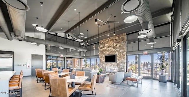 dining area featuring a stone fireplace, beamed ceiling, and a towering ceiling