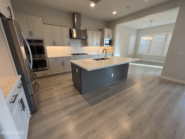 kitchen with extractor fan, light wood-style flooring, a sink, appliances with stainless steel finishes, and decorative backsplash