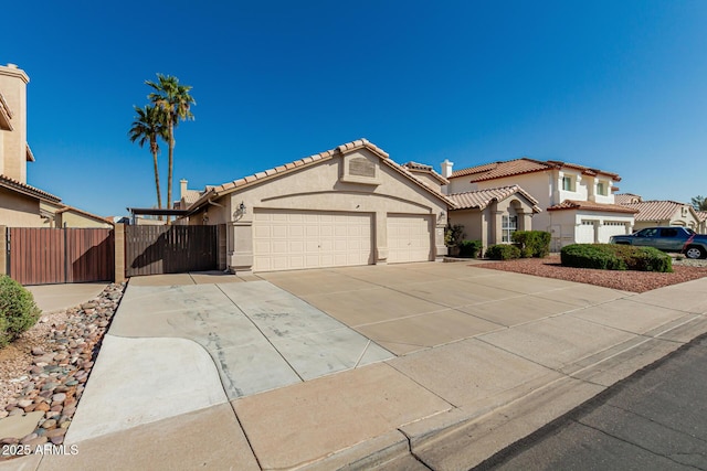 mediterranean / spanish house featuring fence, a tiled roof, concrete driveway, stucco siding, and a garage