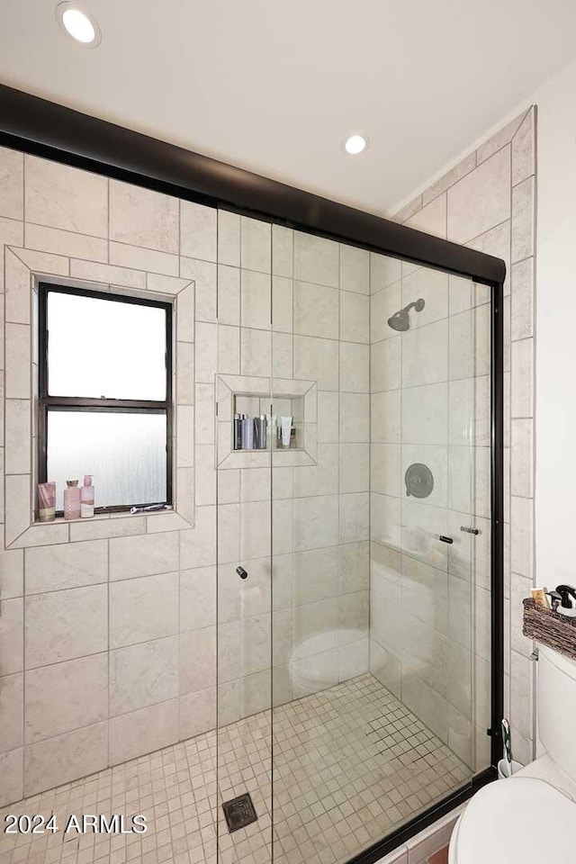 bathroom featuring a shower with door and toilet