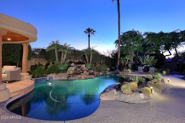 pool at dusk featuring a patio