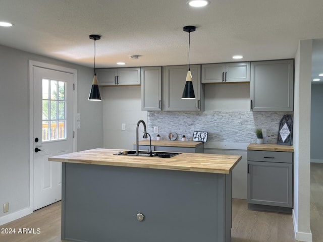 kitchen with light wood-type flooring, butcher block counters, tasteful backsplash, and a kitchen island