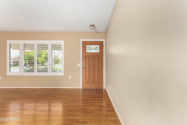 entrance foyer with hardwood / wood-style flooring, a textured ceiling, and vaulted ceiling