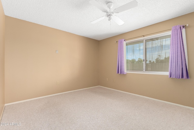 carpeted empty room with ceiling fan and a textured ceiling