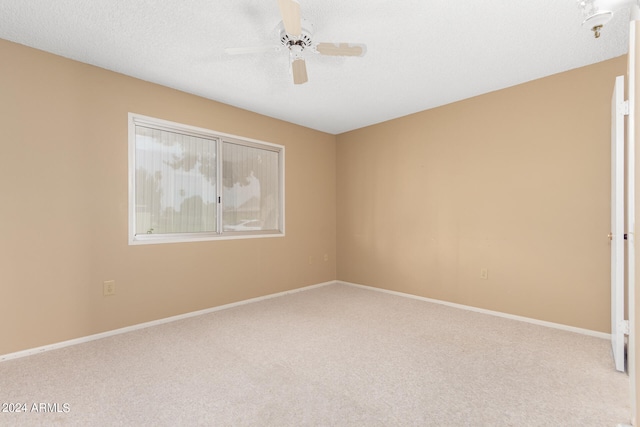 carpeted spare room featuring ceiling fan and a textured ceiling