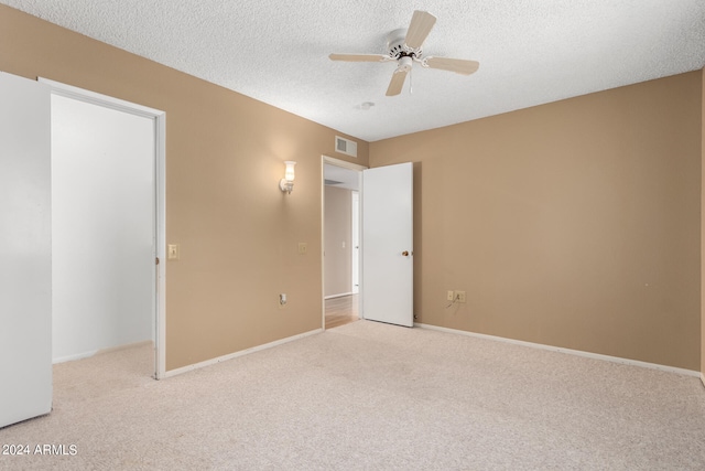 unfurnished bedroom featuring light carpet, a textured ceiling, and ceiling fan