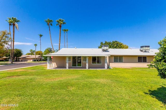 back of property with central AC and a yard