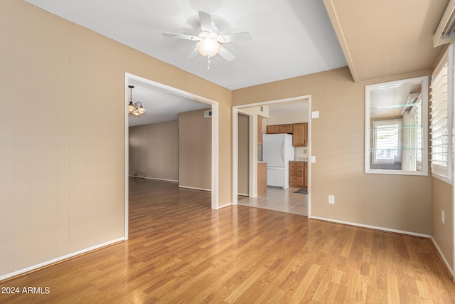 spare room featuring light hardwood / wood-style flooring and ceiling fan with notable chandelier