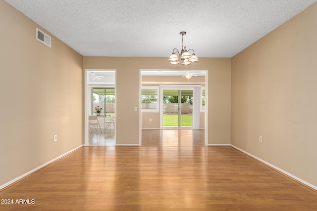 unfurnished room with light hardwood / wood-style floors, an inviting chandelier, and a wealth of natural light