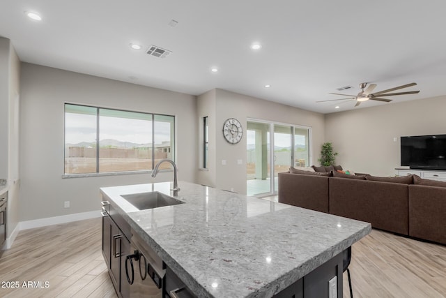 2516 W Joy Ranch Rd, Phoenix, AZ 85086 - kitchen featuring a sink, a kitchen island with sink, light wood-type flooring, open floor plan, and light stone counters