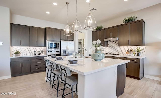 16336 W Jackson St, Goodyear, AZ 85338 - kitchen featuring stainless steel appliances, dark brown cabinetry, a kitchen bar, and recessed lighting