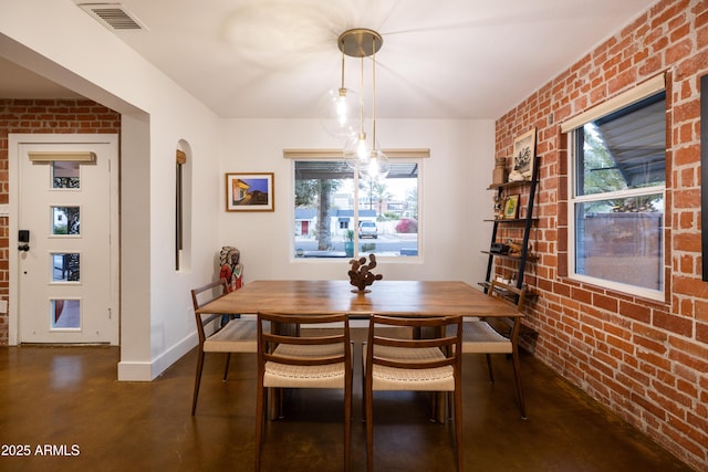 dining space featuring breakfast area, a healthy amount of sunlight, and brick wall