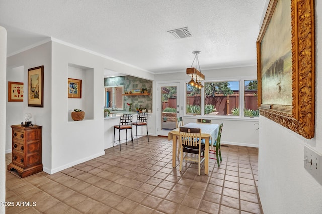tiled dining area with ornamental molding, a textured ceiling, and baseboards