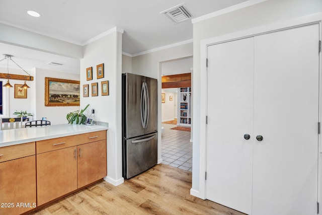 kitchen featuring freestanding refrigerator, light countertops, light wood finished floors, crown molding, and baseboards