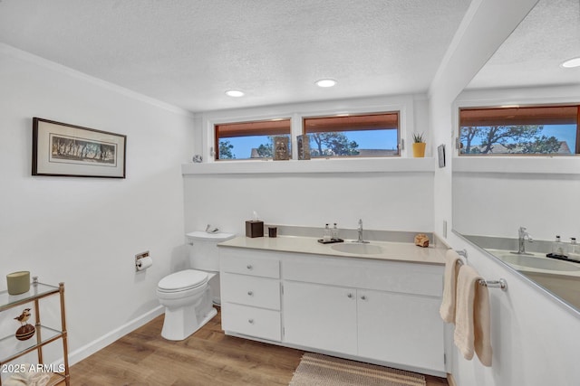 bathroom with a textured ceiling, toilet, healthy amount of natural light, recessed lighting, and wood finished floors