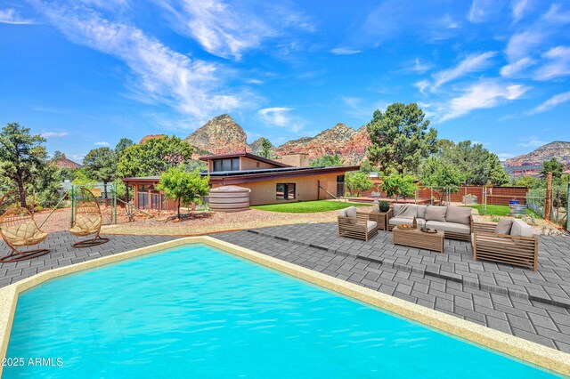 view of swimming pool featuring an outdoor living space, a patio, a mountain view, and a fenced backyard