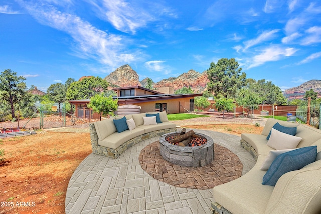 view of patio featuring a fenced backyard, a mountain view, and an outdoor living space with a fire pit
