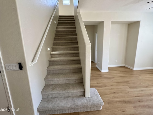 stairway featuring wood finished floors, visible vents, and baseboards