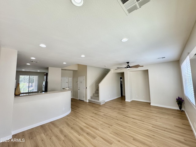 unfurnished living room featuring baseboards, light wood-type flooring, stairway, and recessed lighting