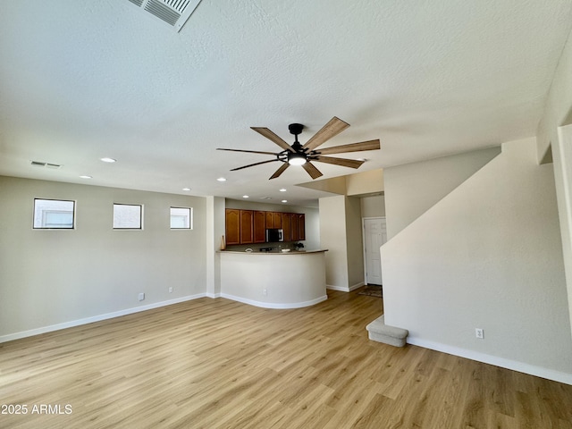 unfurnished living room featuring light wood finished floors, visible vents, ceiling fan, and baseboards