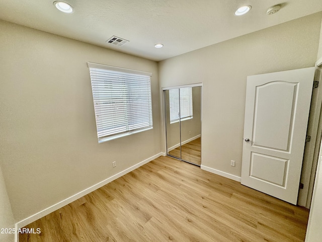 unfurnished bedroom featuring recessed lighting, light wood-style flooring, a closet, baseboards, and visible vents