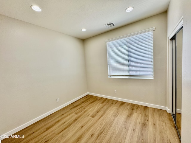 spare room with light wood finished floors, recessed lighting, visible vents, and baseboards