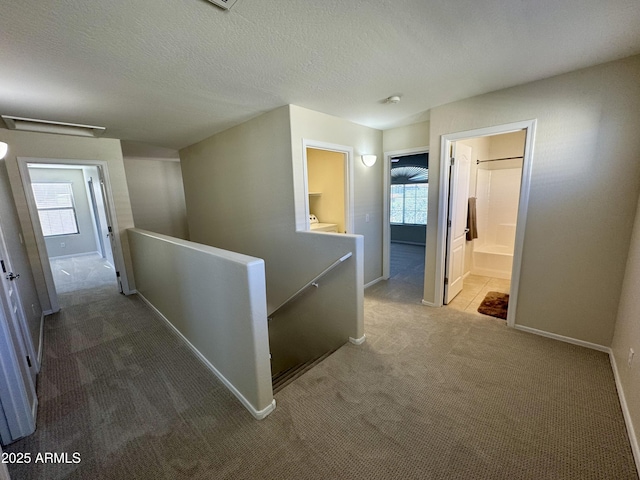 corridor featuring attic access, a healthy amount of sunlight, an upstairs landing, and carpet floors
