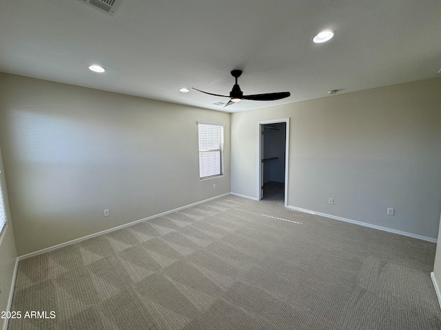 unfurnished bedroom with recessed lighting, ceiling fan, a walk in closet, light carpet, and baseboards