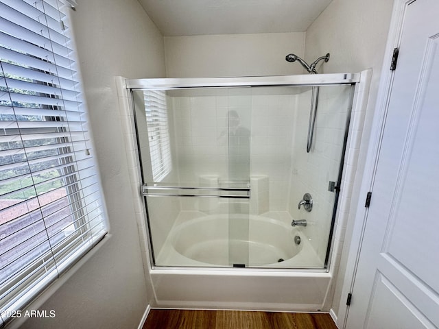 full bath with wood finished floors, shower / bath combination with glass door, and baseboards