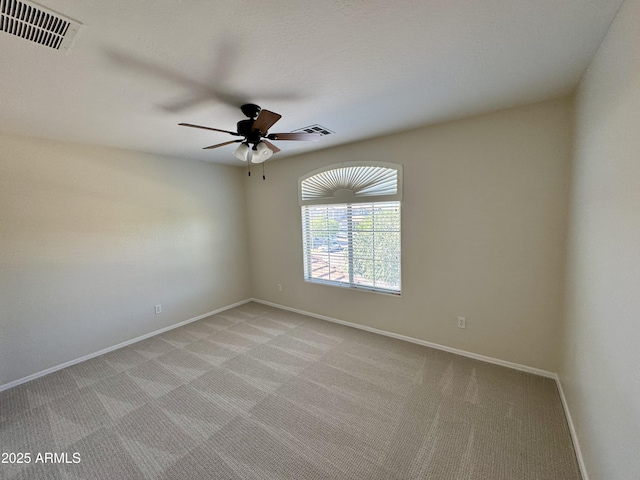 empty room featuring baseboards, visible vents, a ceiling fan, and light carpet