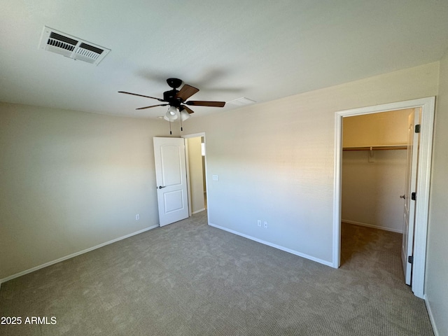 unfurnished bedroom with carpet flooring, visible vents, baseboards, a spacious closet, and a ceiling fan