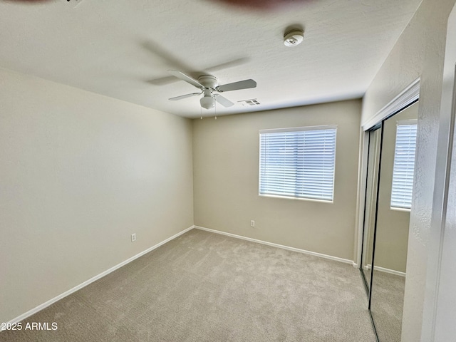 unfurnished bedroom with carpet flooring, visible vents, ceiling fan, baseboards, and a closet