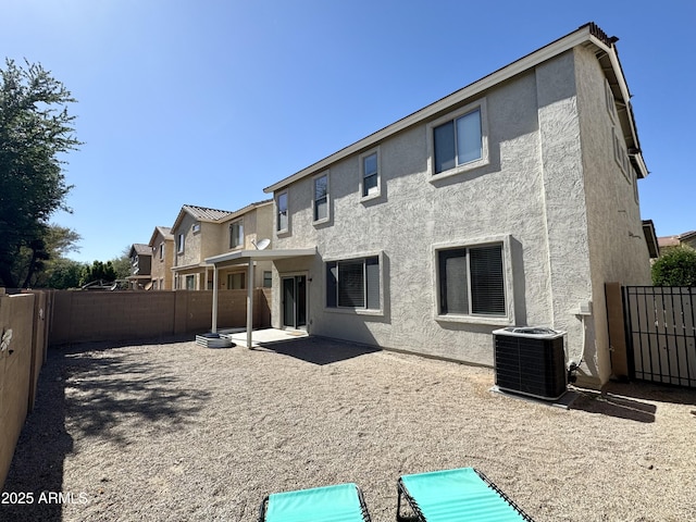 rear view of property featuring stucco siding, central AC unit, a patio, and a fenced backyard