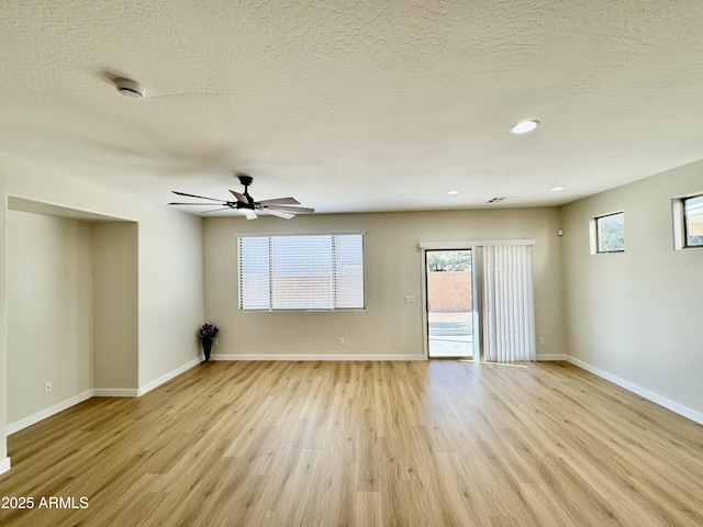 empty room featuring a ceiling fan, baseboards, a textured ceiling, and light wood-style floors
