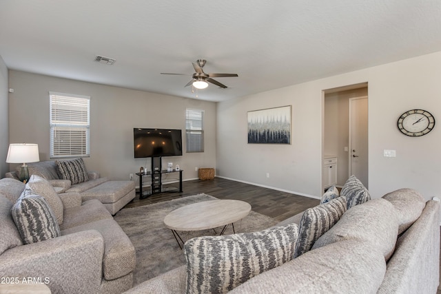 living room featuring dark wood-type flooring, ceiling fan, and a wealth of natural light