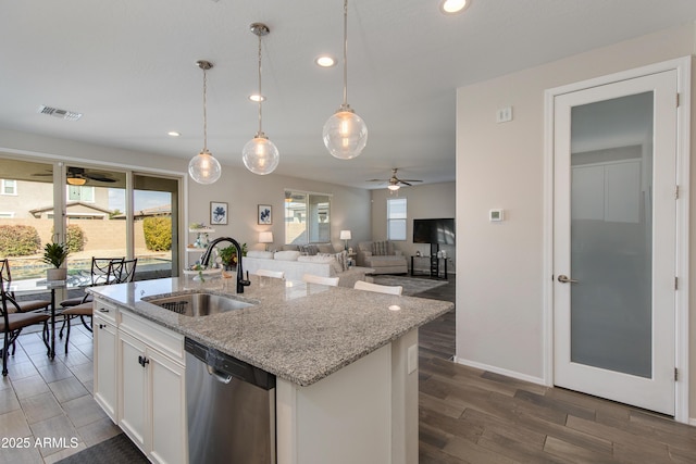 kitchen with stainless steel dishwasher, a kitchen island with sink, sink, and white cabinets