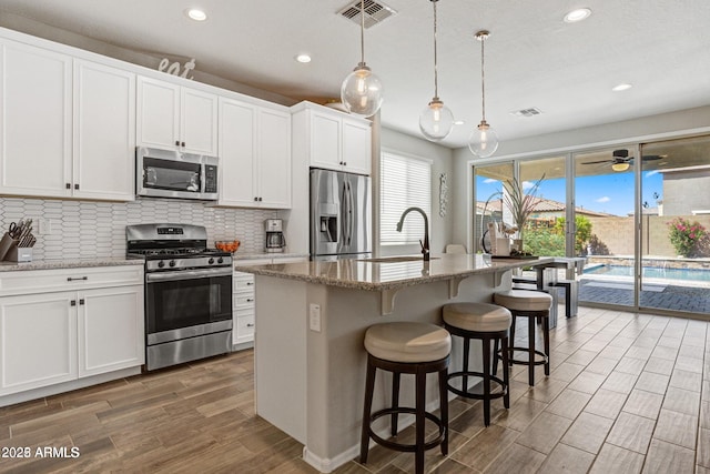 kitchen with white cabinetry, an island with sink, appliances with stainless steel finishes, and sink