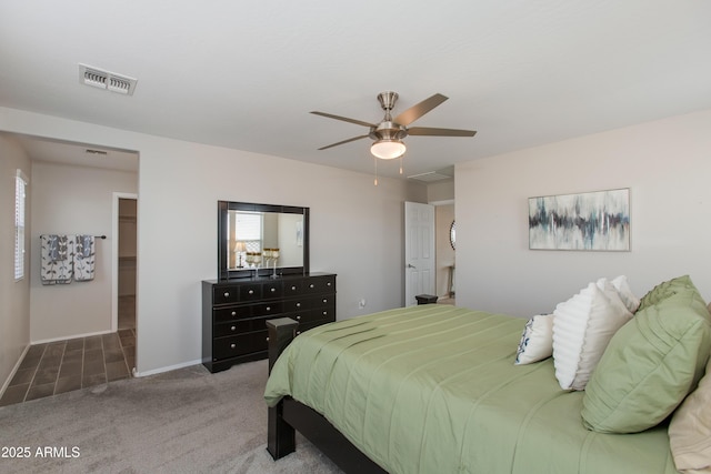 bedroom with a walk in closet, carpet flooring, and ceiling fan