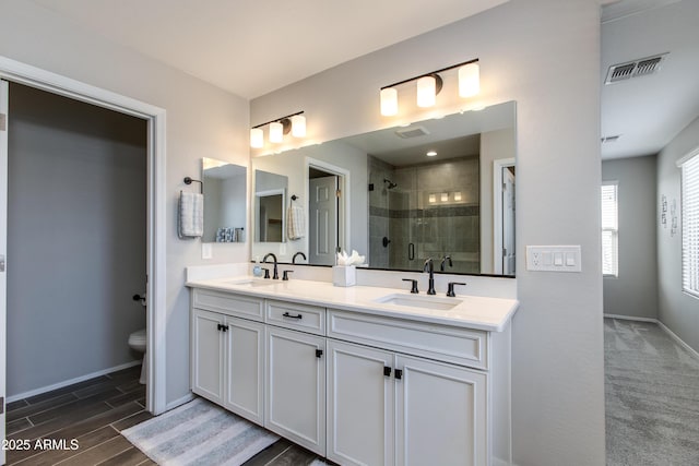 bathroom featuring vanity, a shower with shower door, and toilet