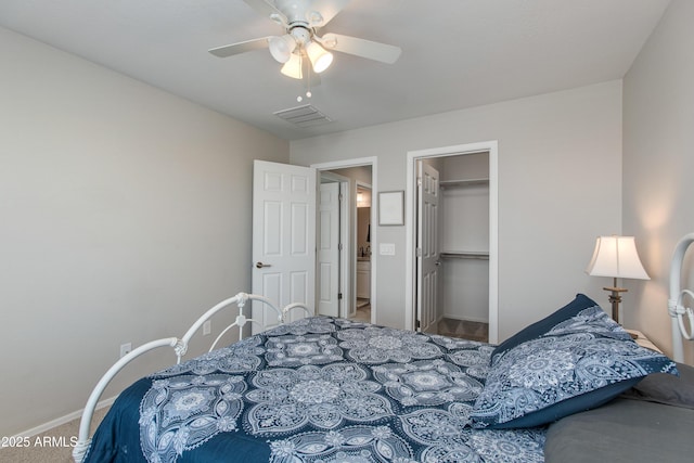 bedroom featuring a walk in closet, a closet, ceiling fan, and carpet flooring