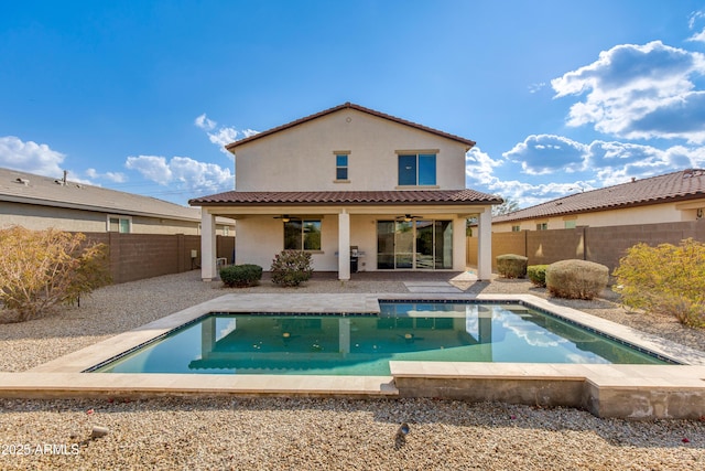 rear view of house with a fenced in pool, a patio area, and ceiling fan