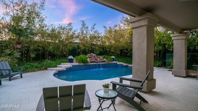 pool at dusk featuring a patio and pool water feature