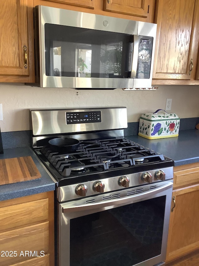 kitchen with dark countertops, brown cabinetry, and stainless steel appliances