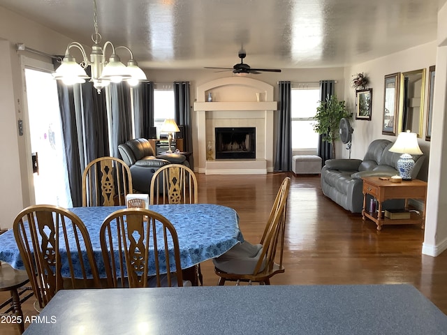 dining area featuring ceiling fan with notable chandelier, a fireplace, and wood finished floors